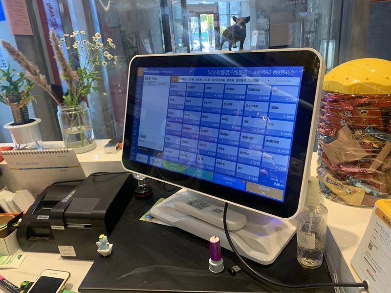 奶茶店的收银机屏幕被奶茶冲击后有了裂痕,店主还特地在上面摆上了野猪摆件。