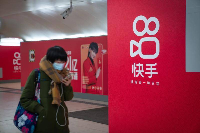 2021年2月3日,快手在北京地铁站做宣传,行人匆匆走过。来源:视觉中国