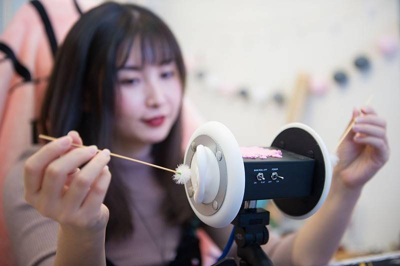 ASMR主播把鹅毛棒放进“模拟耳朵”轻轻掏耳。图片:CFP